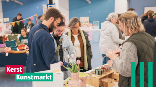 Mensen staan voor een tafel van een kraampje dat handgemaakte keramiek verkoopt.