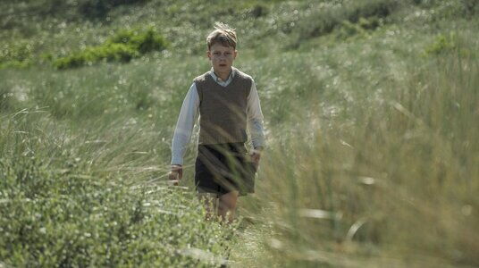 Filmstill, een jongen in de duinen